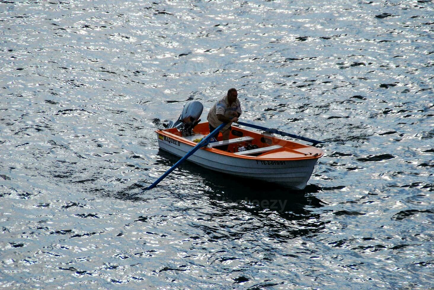 a man in a small boat on the water photo