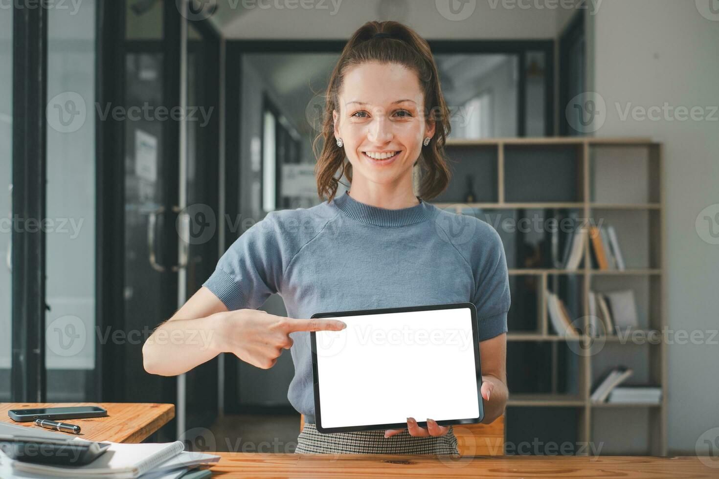 Smiling woman holding digital tablet with blank white desktop screen for product display, Mockup digital tablet with blank screen. photo