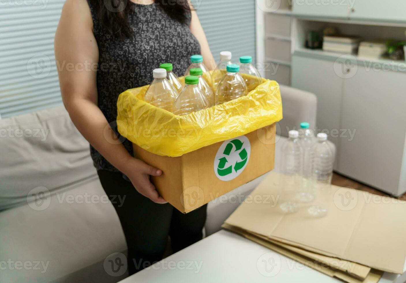 Home recycle eco green zero concept Woman throwing empty plastic bottle in recycling bin with yellow garbage bags at home. photo