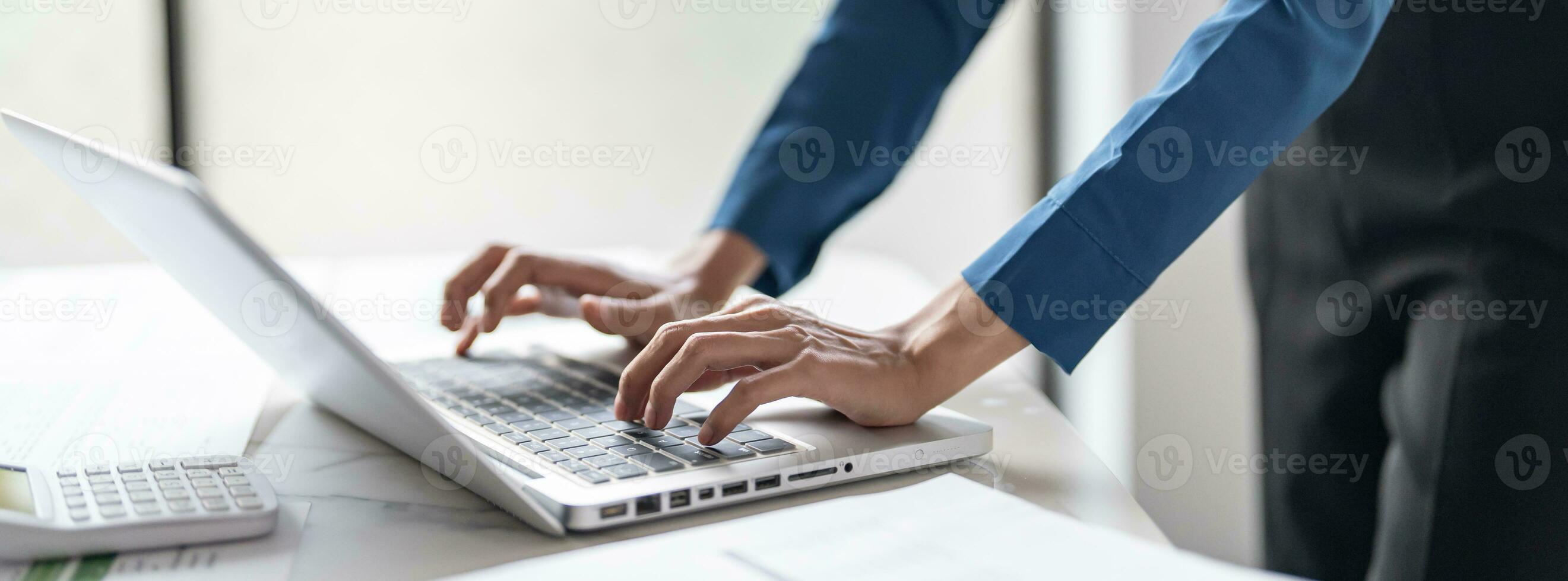 Working by using a laptop computer on wooden table. Hands typing photo