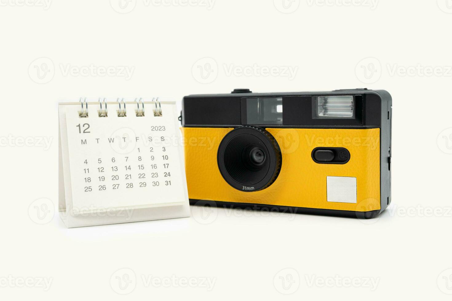 Simple desk calendar for December 2023 and film camera isolated on white background. Calendar and holiday concept with copy space. photo