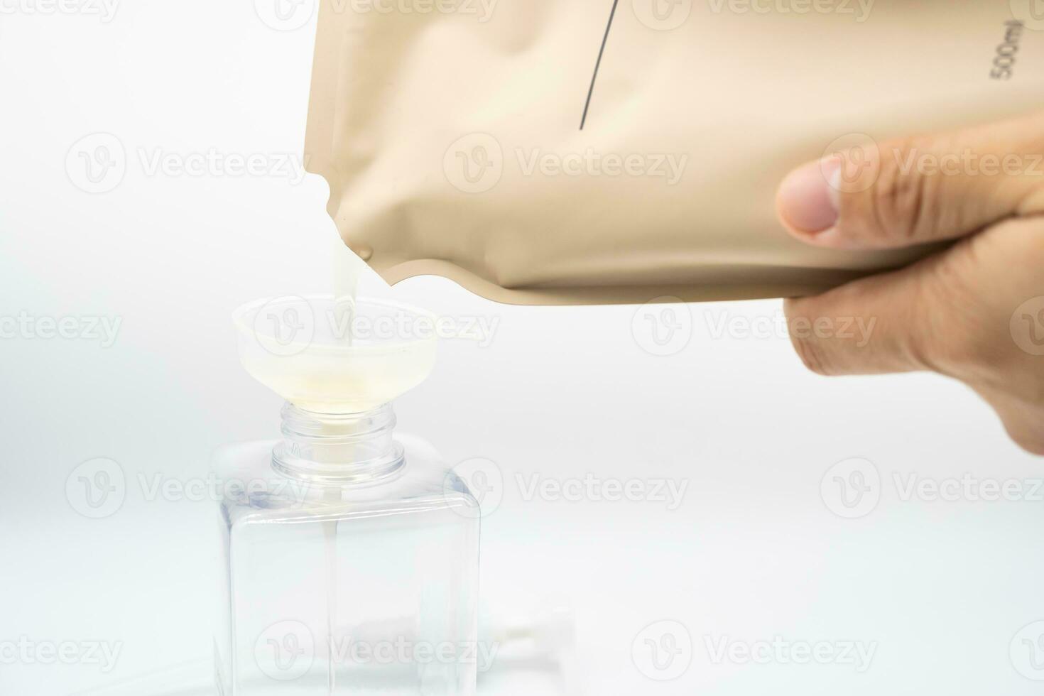 A man fills a dispenser with liquid soap by pouring it from a refill to reduce plastic waste. Soap or Shampoo for refill. photo