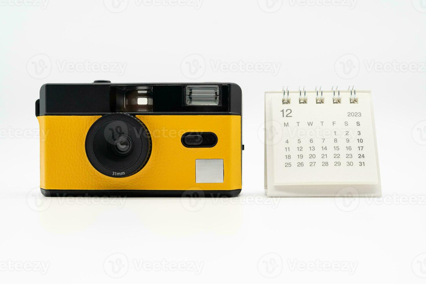 Simple desk calendar for December 2023 and film camera isolated on white background. Calendar and holiday concept with copy space. photo