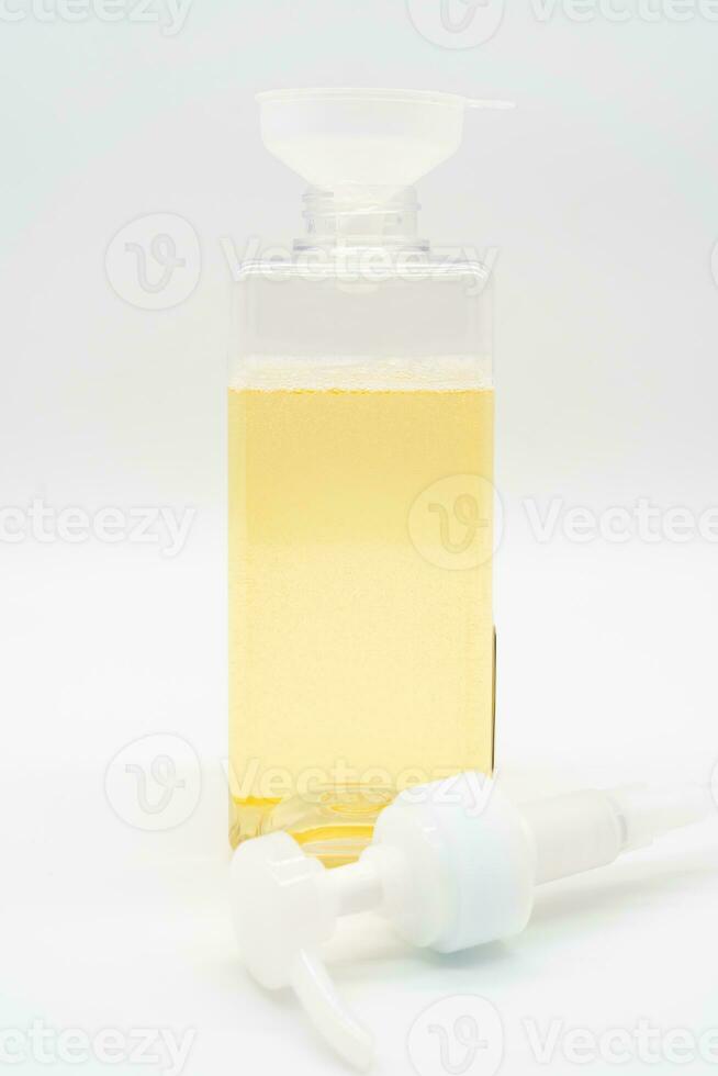 Pour yellow liquid through a funnel. Fill a dispenser with liquid soap or shampoo by pouring it from a refill to reduce plastic waste. Sustainable Zero Waste photo