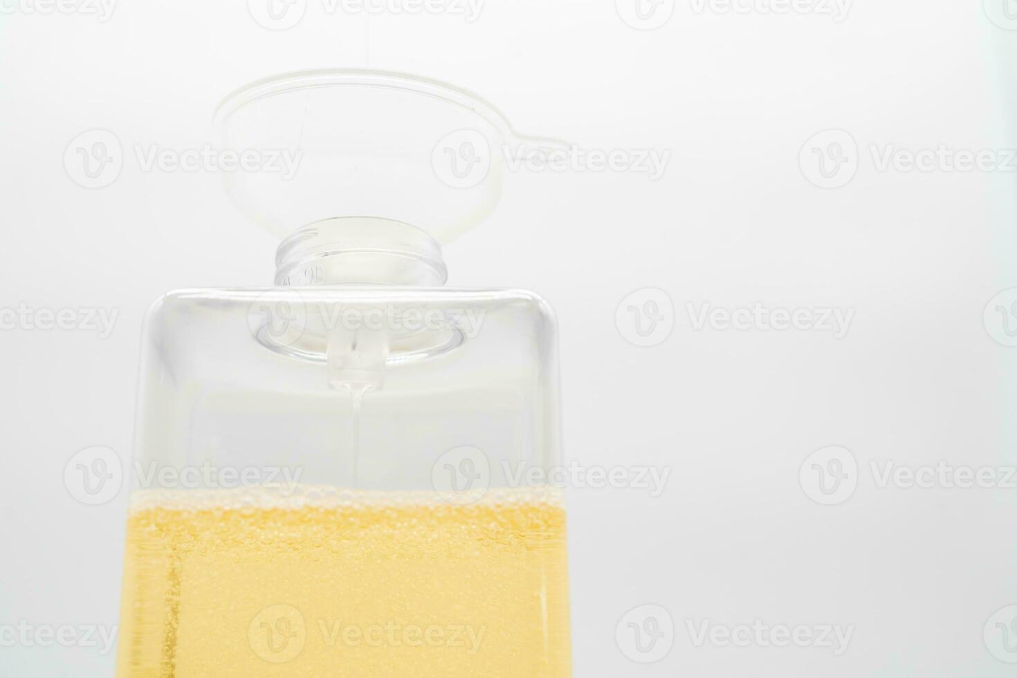 Pour yellow liquid through a funnel. Fill a dispenser with liquid soap or shampoo by pouring it from a refill to reduce plastic waste. Sustainable Zero Waste photo