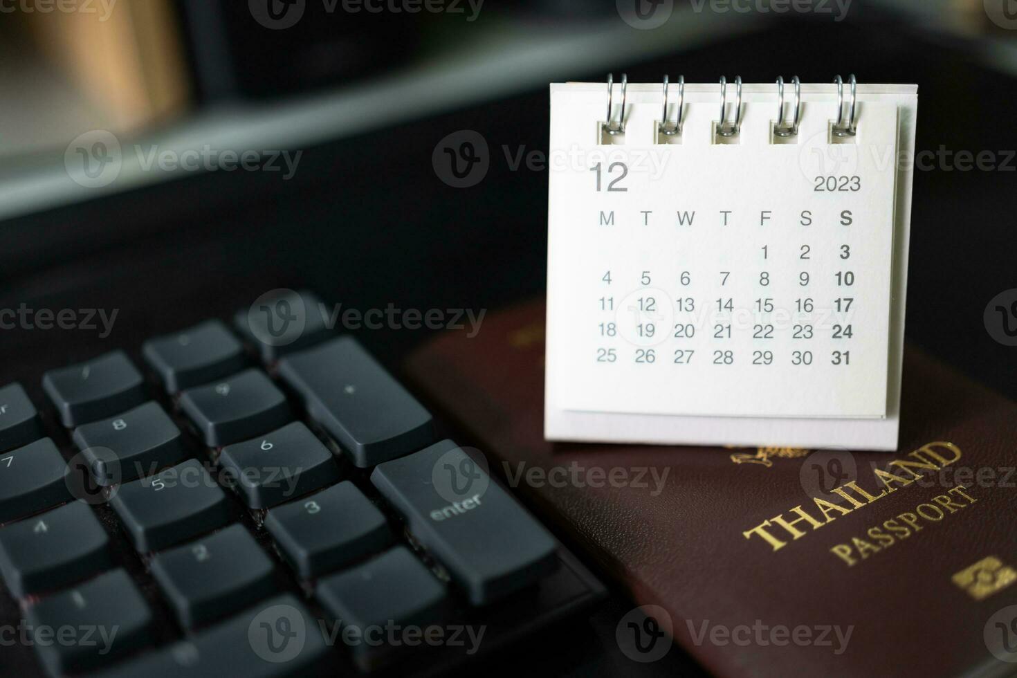 Simple desk calendar for December 2023 and Passport. Calendar and holiday concept with passport on the desk. copy space. photo