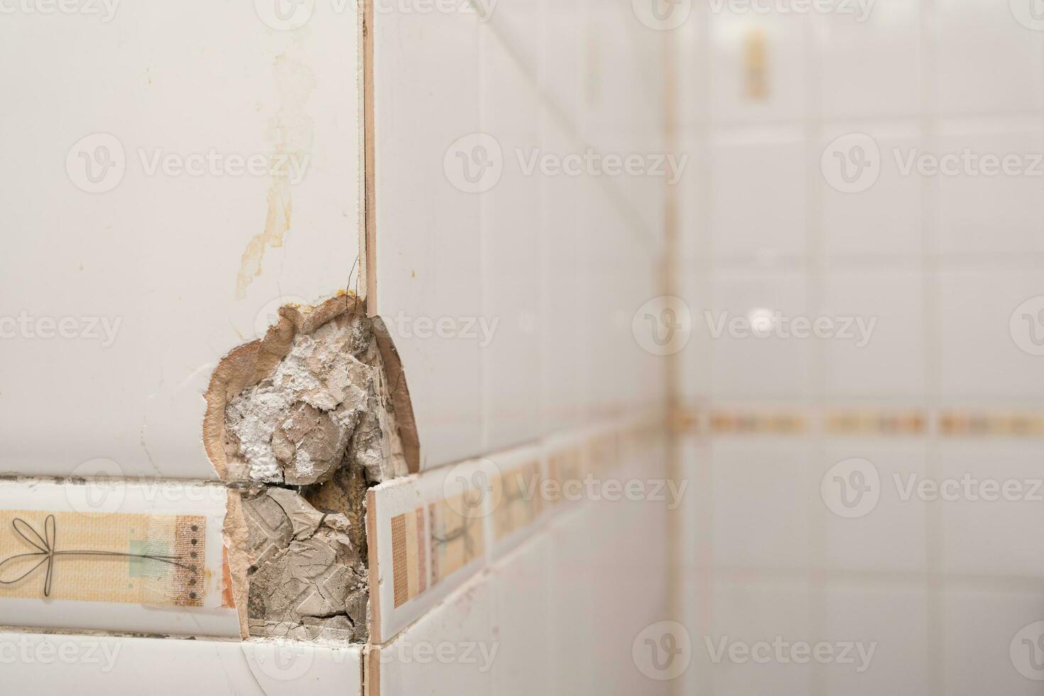 Close up of a cracked ceramic tiles surface. Cracked, broken bathroom wall tiles or panels. photo