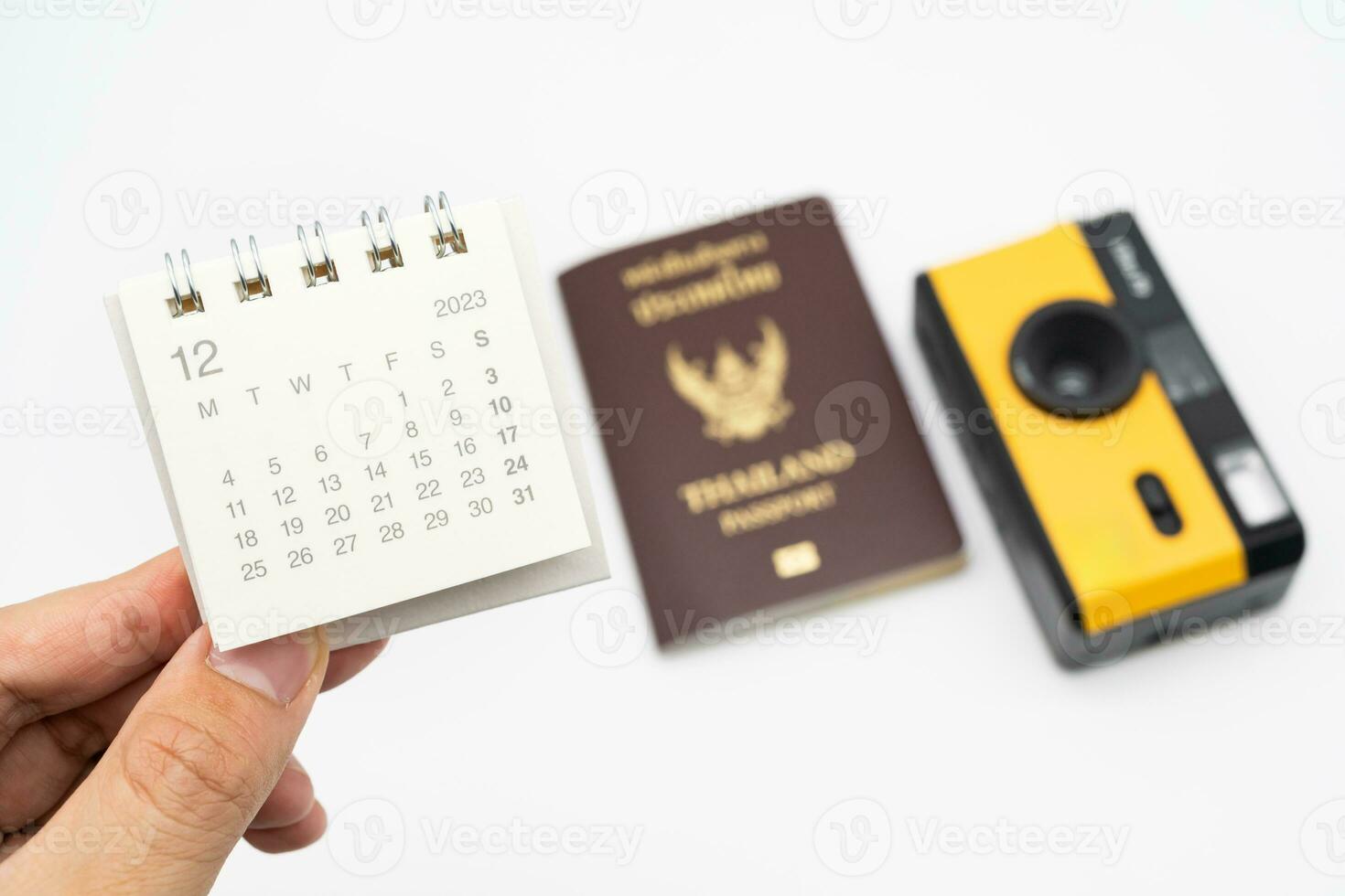 Simple desk calendar for December 2023 on palm. Calendar and holiday concept with passport and camera on the background. photo