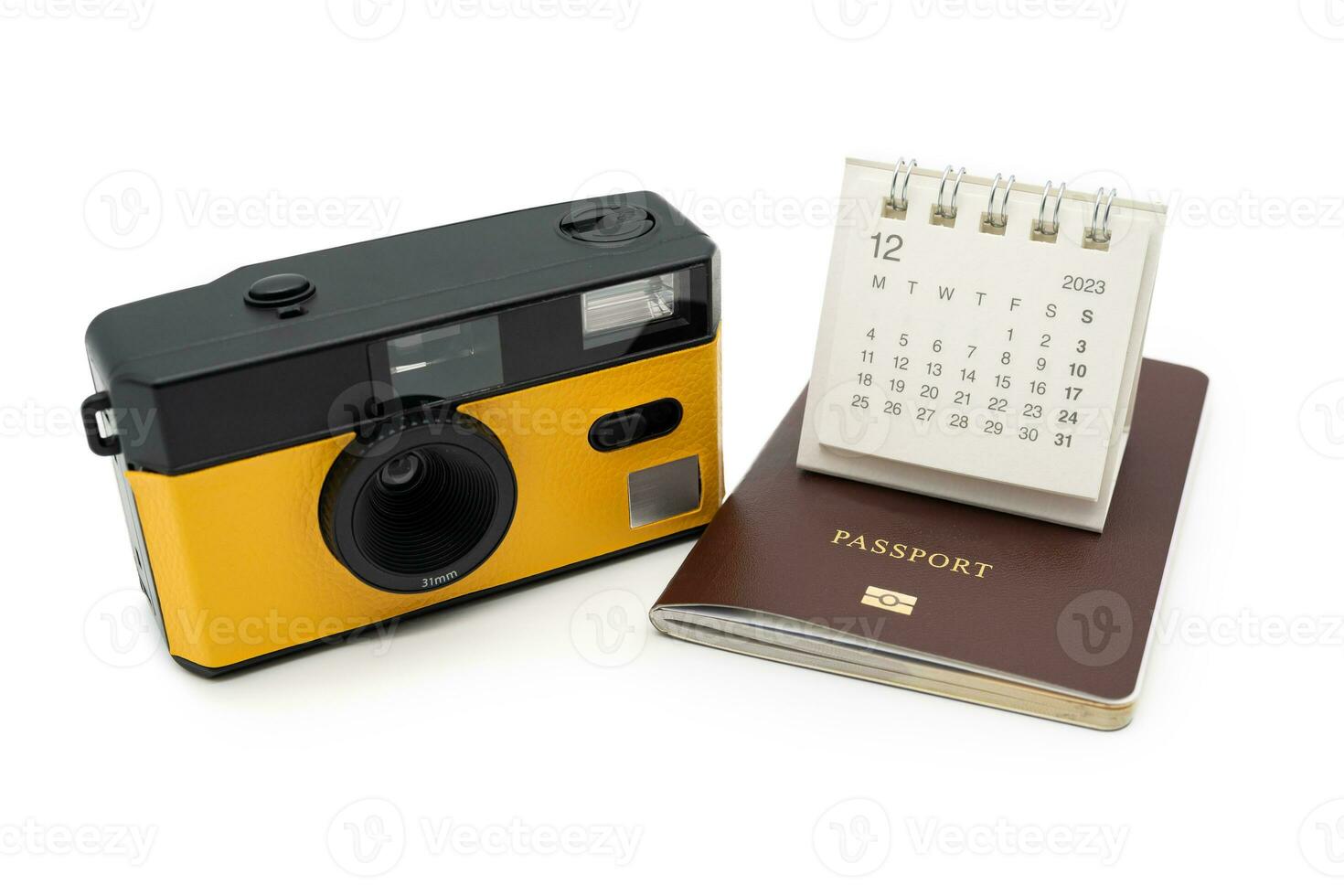 Simple desk calendar for December 2023 on Passport and Film Camera. Calendar and holiday concept with passport and camera isolate on white background. photo