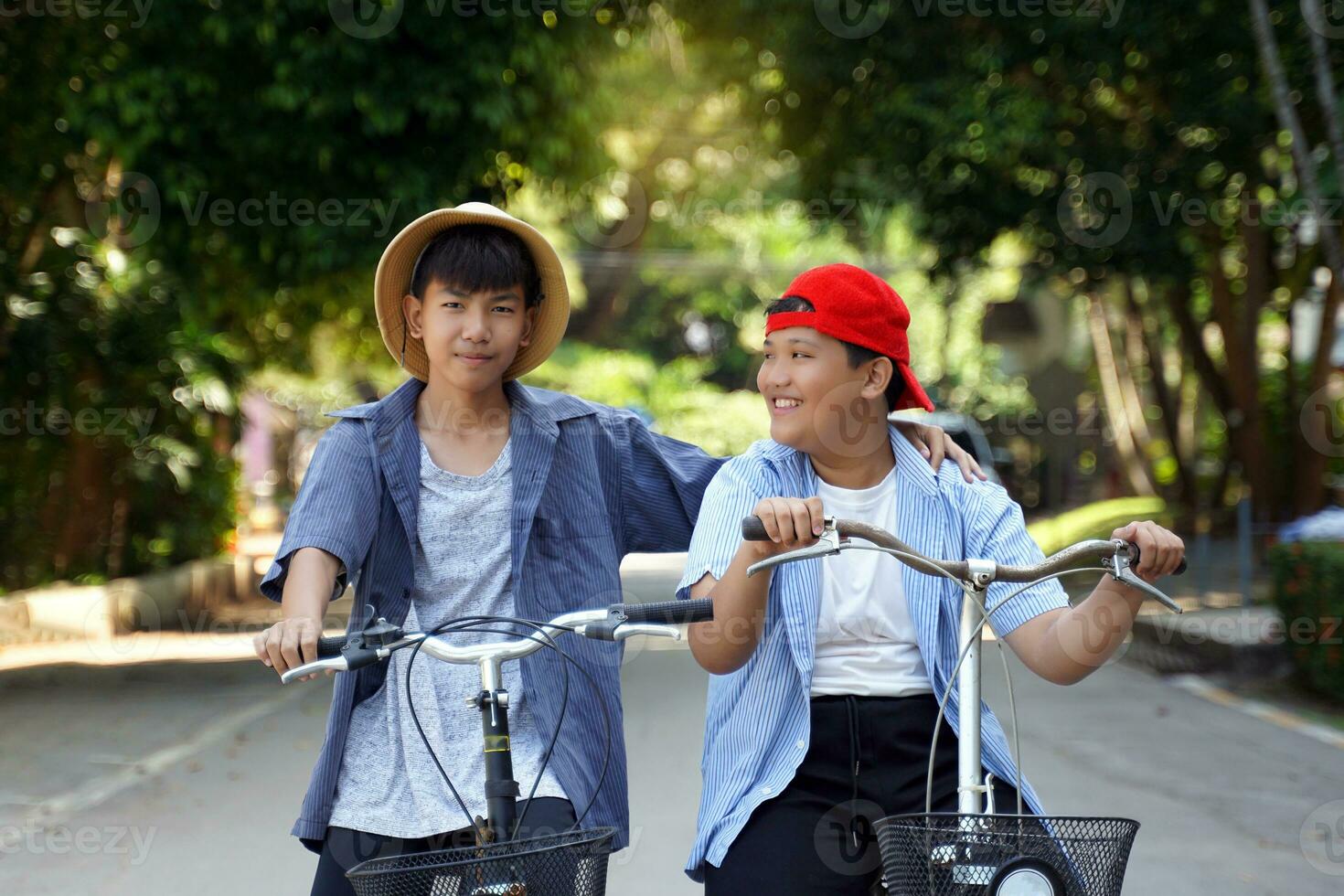 dos asiático Niños quien son amigos paseo bicicletas en el local parque en día festivo. ellos son ambos contento y teniendo divertida. fiesta actividad concepto. suave y selectivo enfocar. foto