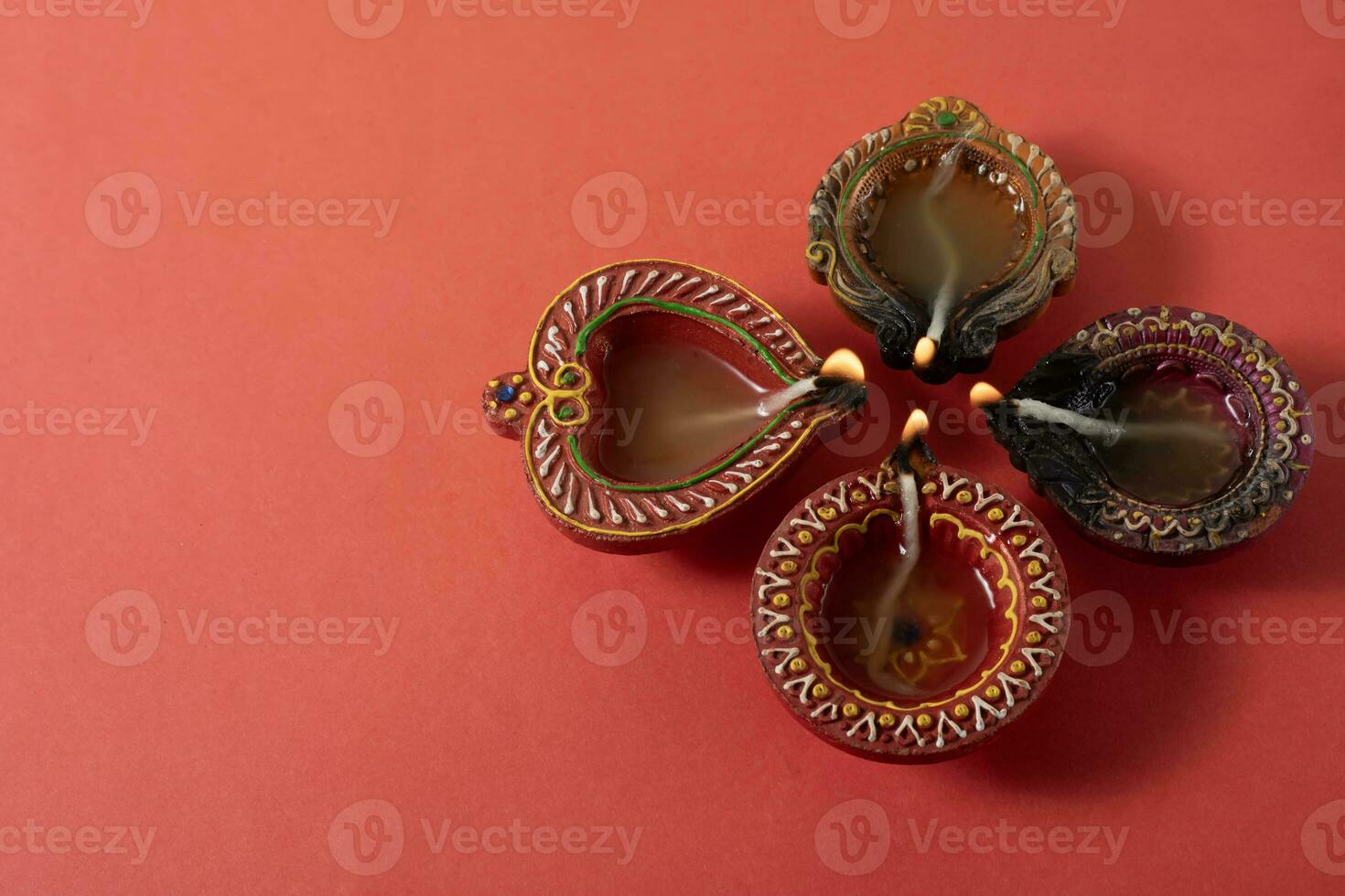 Happy Diwali and Kartika Deepam Festival Greetings - Clay diya oil lamps lit in celebration of Hindu festival of lights Diwali and Kartika Deepa on red background. photo