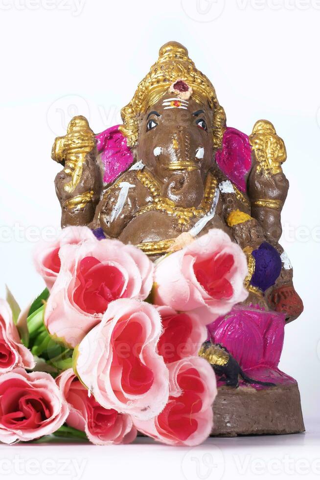 A Ganesh statue made of clay is also a rose flower on white background. photo