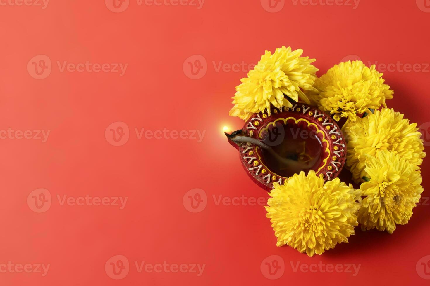 Happy Diwali and Kartika Deepam Festival Greetings - Colorful clay Deepam with yellow flowers on red background photo