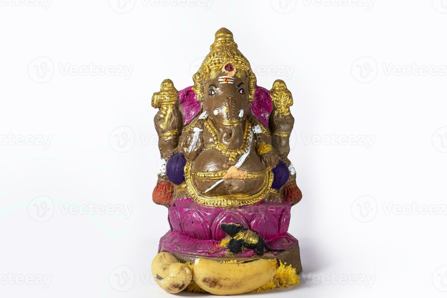 Ganesh chaturthi - A beautifully painted clay Ganesh statue on a white background is celebrated with flowers and bananas. photo