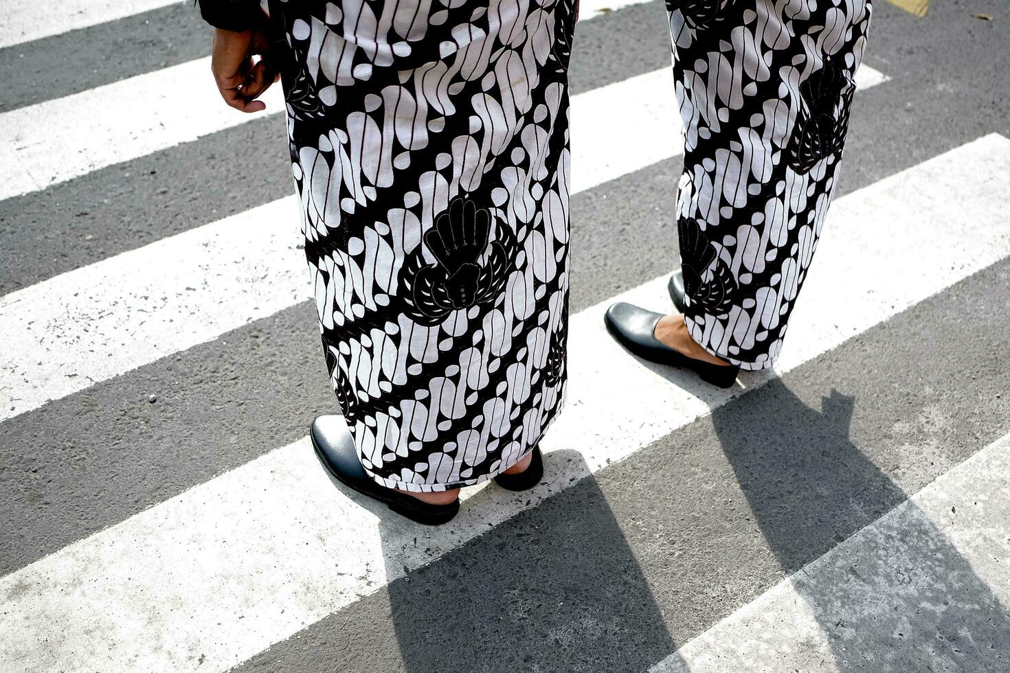 a person standing on a crosswalk wearing black and white pants photo