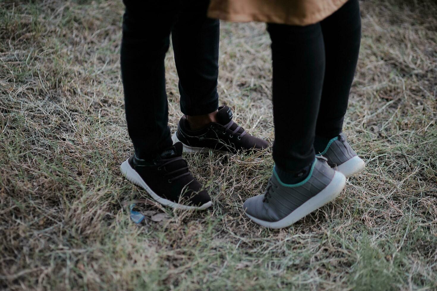 two people standing in the grass with their shoes on photo