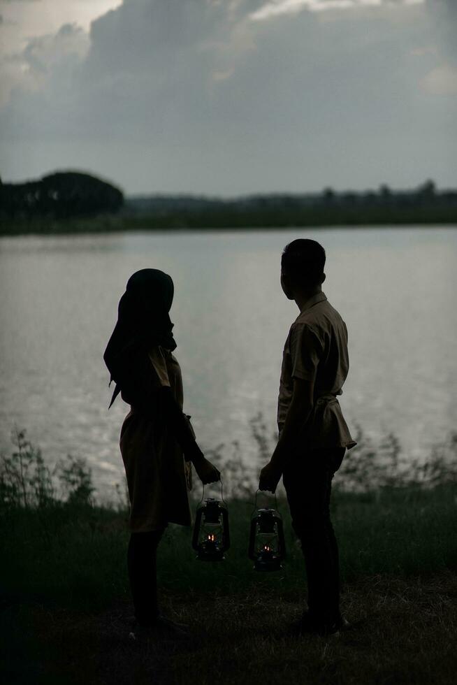 two people holding lanterns by the water photo