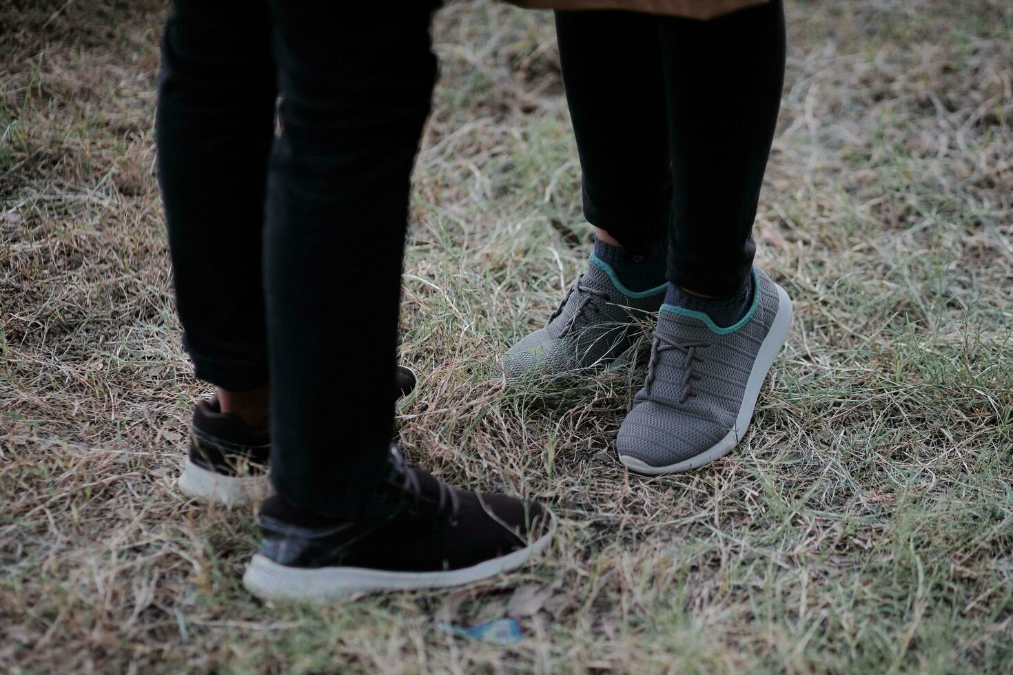 two people standing in the grass wearing sneakers photo