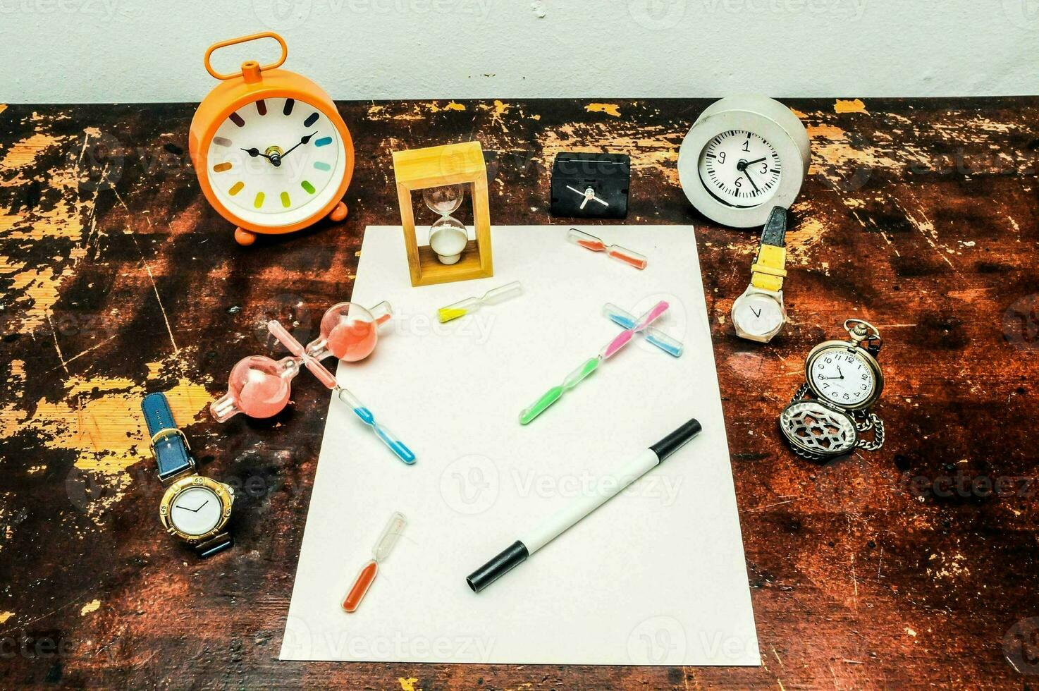 a table with various items including clocks, pens, and a pen photo