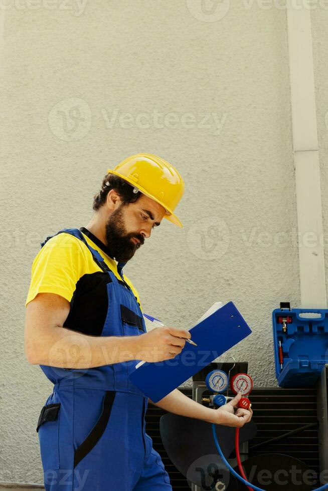 Competent mechanic filling out revision of insurance contract for home owner to sign after finishing repairments on air conditioner. Expert repairman writing down cost of fixed internal components photo