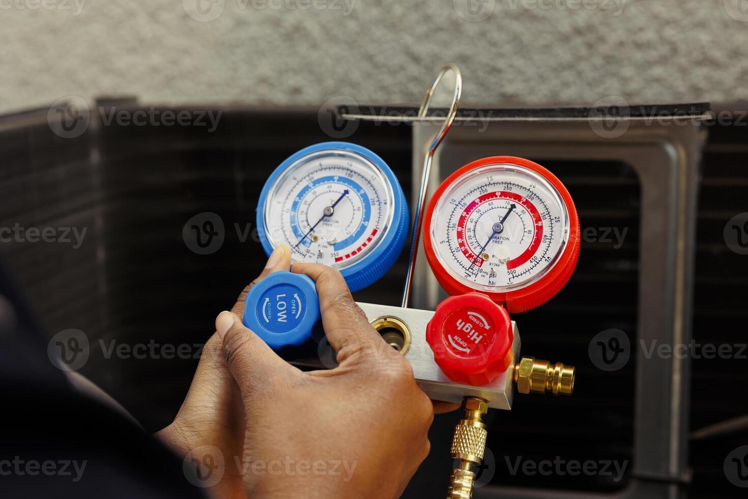 Pressure meters able to detect damaged expansion valve and excessive freon in condenser, close up. Knowledgeable professional using manifold indicator to read refrigerant levels in outside hvac system photo