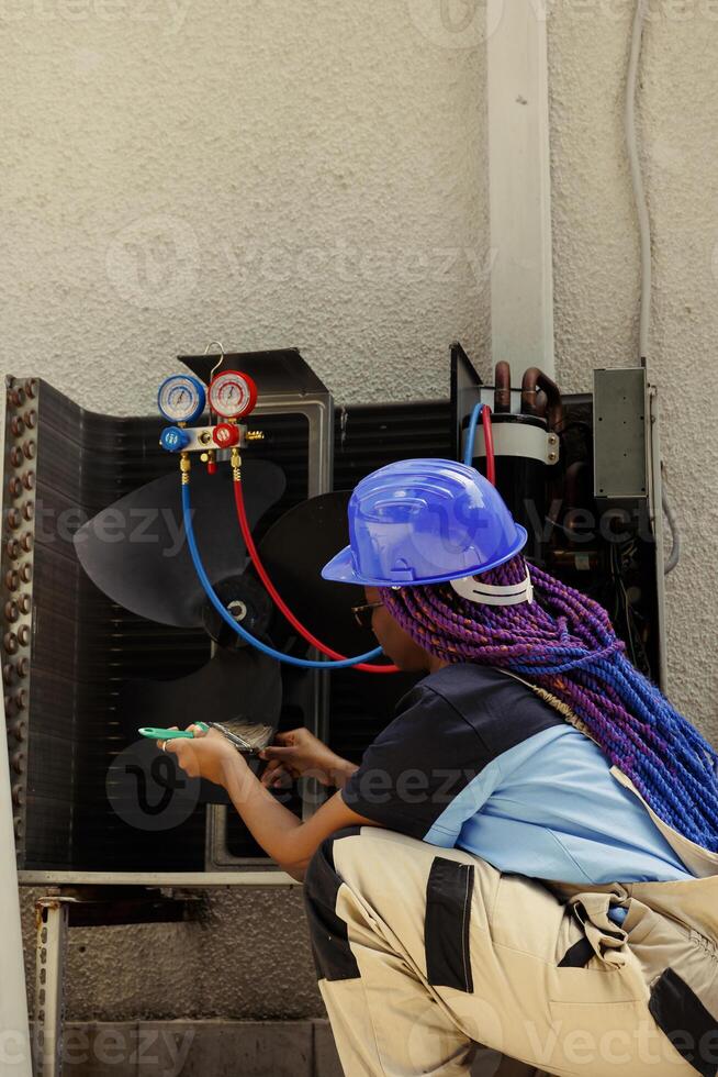 Knowleadgeable engineer removing layer of dust from blower fan to prevent ventilation system malfunction. Efficient technician cleaning internal component to stop risk of air conditioner overheating photo