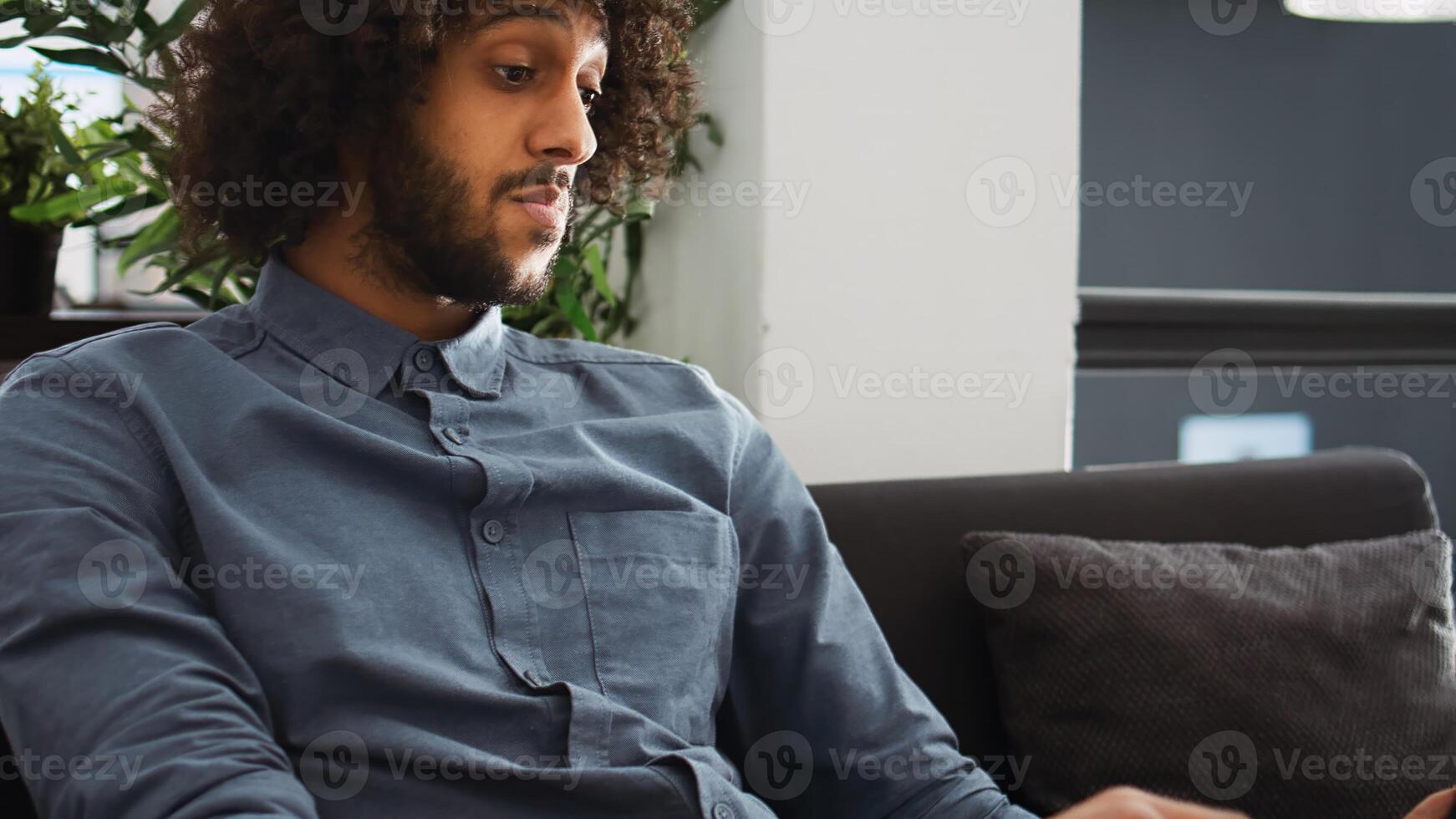 Middle eastern worker on videocall, meeting with executive board to present marketing progress, open floor plan shared office. Businessman attends briefing videoconference at job. photo