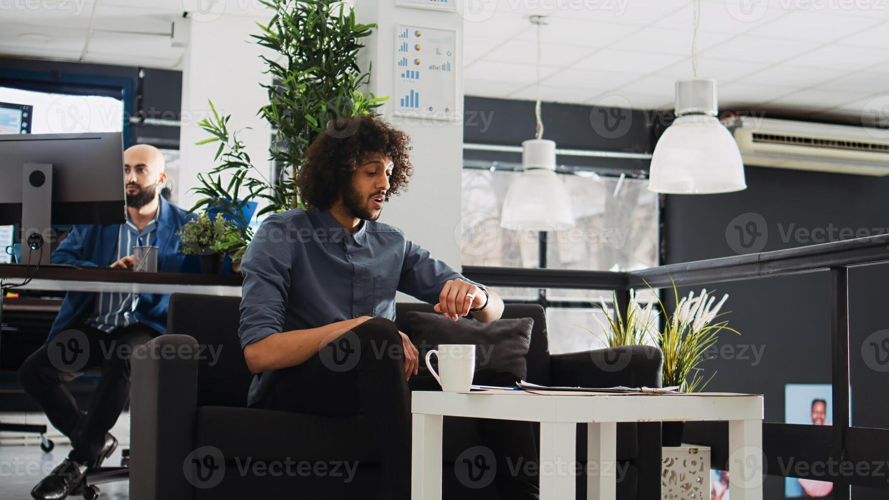 Employee using smartwatch for videocall, entering professional meeting call with modern gadget. Small business owner working on development plan, company workplace. Tripod shot. photo