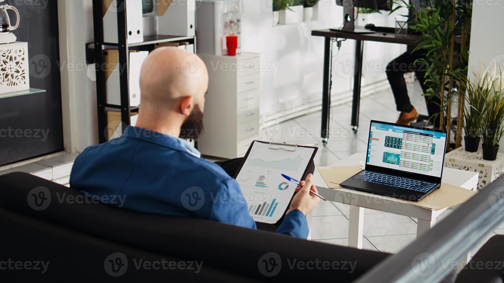 Startup analyst comparing files with data on laptop, looking at annual statistics reports to increase sales and profit for unicorn business. Employee doing professional research in office. photo
