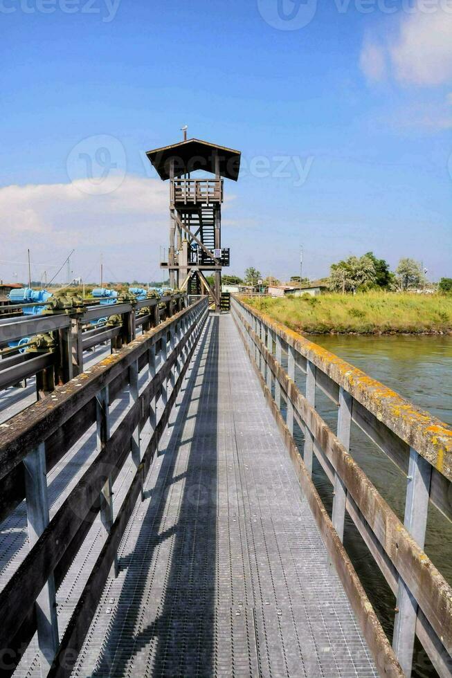 a wooden bridge over a river with a guard tower photo