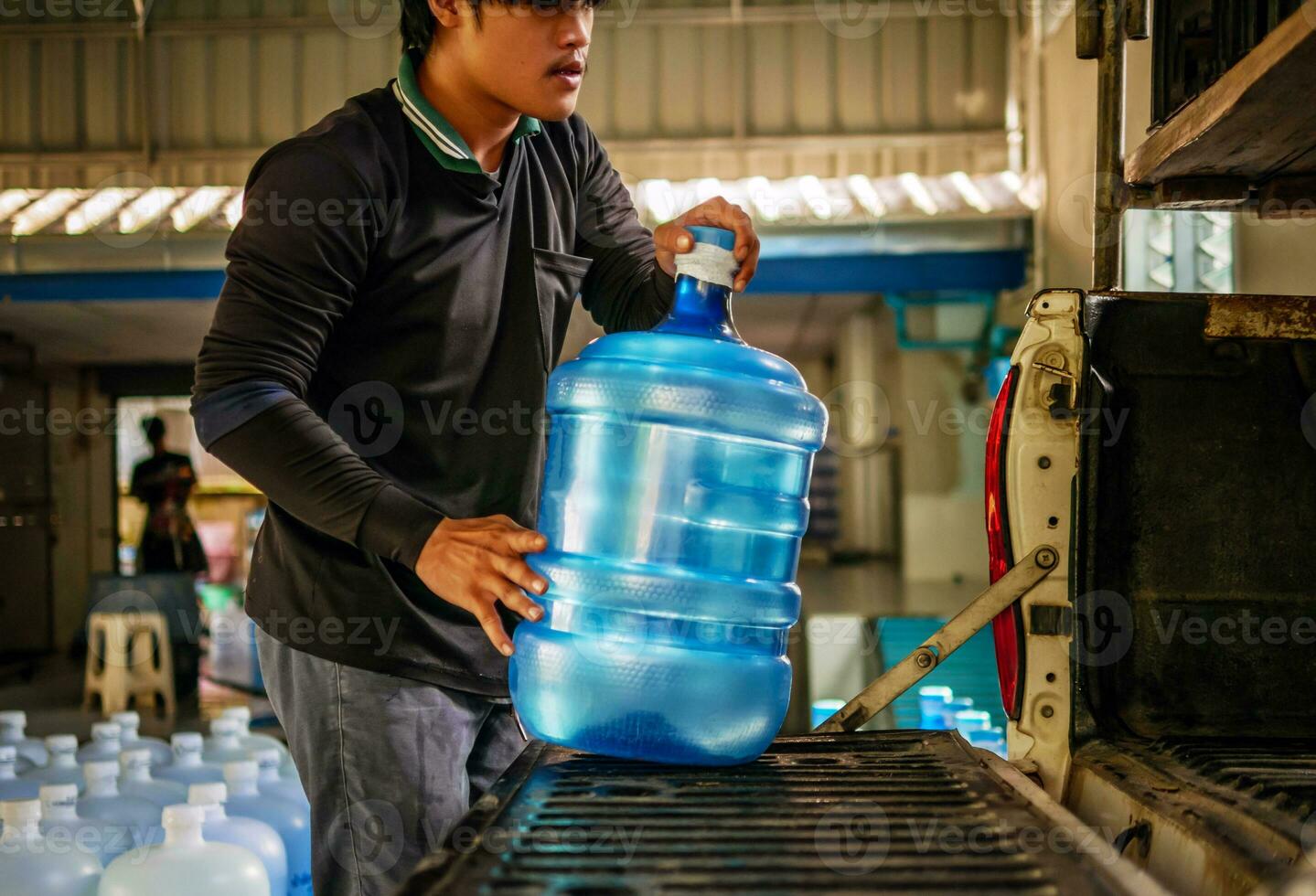 Workers lift drinking water clear and clean in blue plastic gallon into the back of a transport truck purified drinking water inside the production line to prepare for sale.small business photo