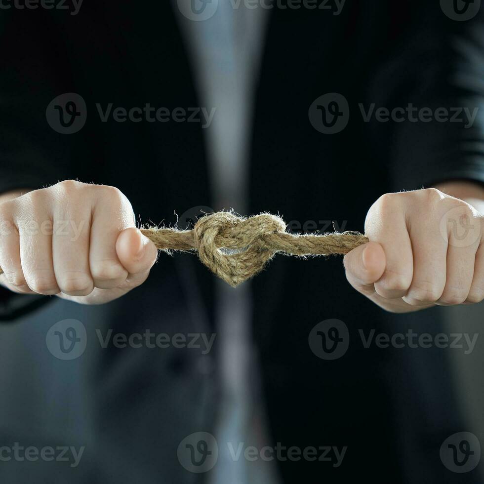 A heart-shaped knot. The businessman's hands tighten the rope knot against background of suit in blur. The concept of feeling. photo
