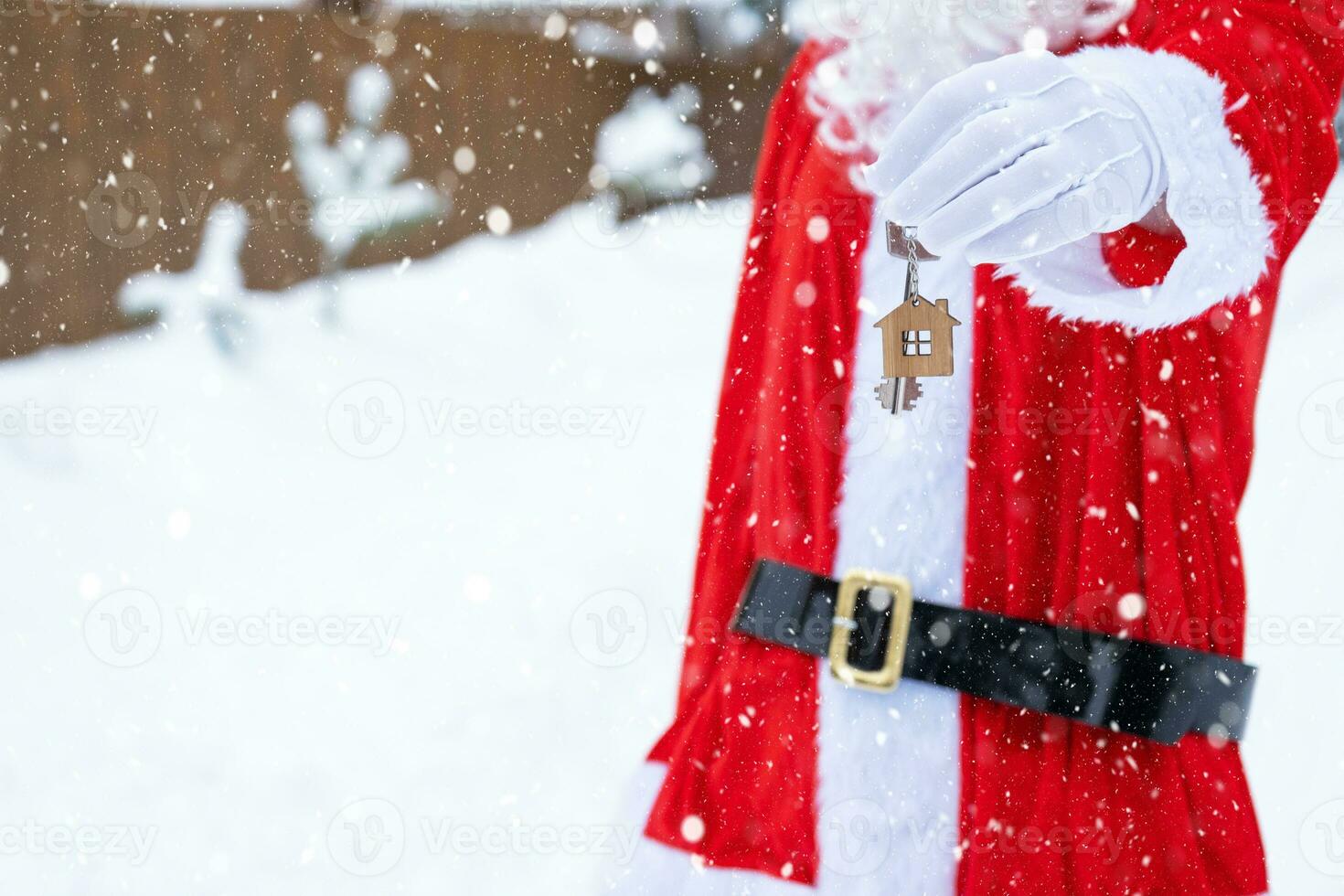 House key with keychain cottage in hands of Santa Claus outdoor in snow. Deal for real estate, purchase, construction, relocation, mortgage. Cozy home. Merry Christmas, new year booking event and hall photo