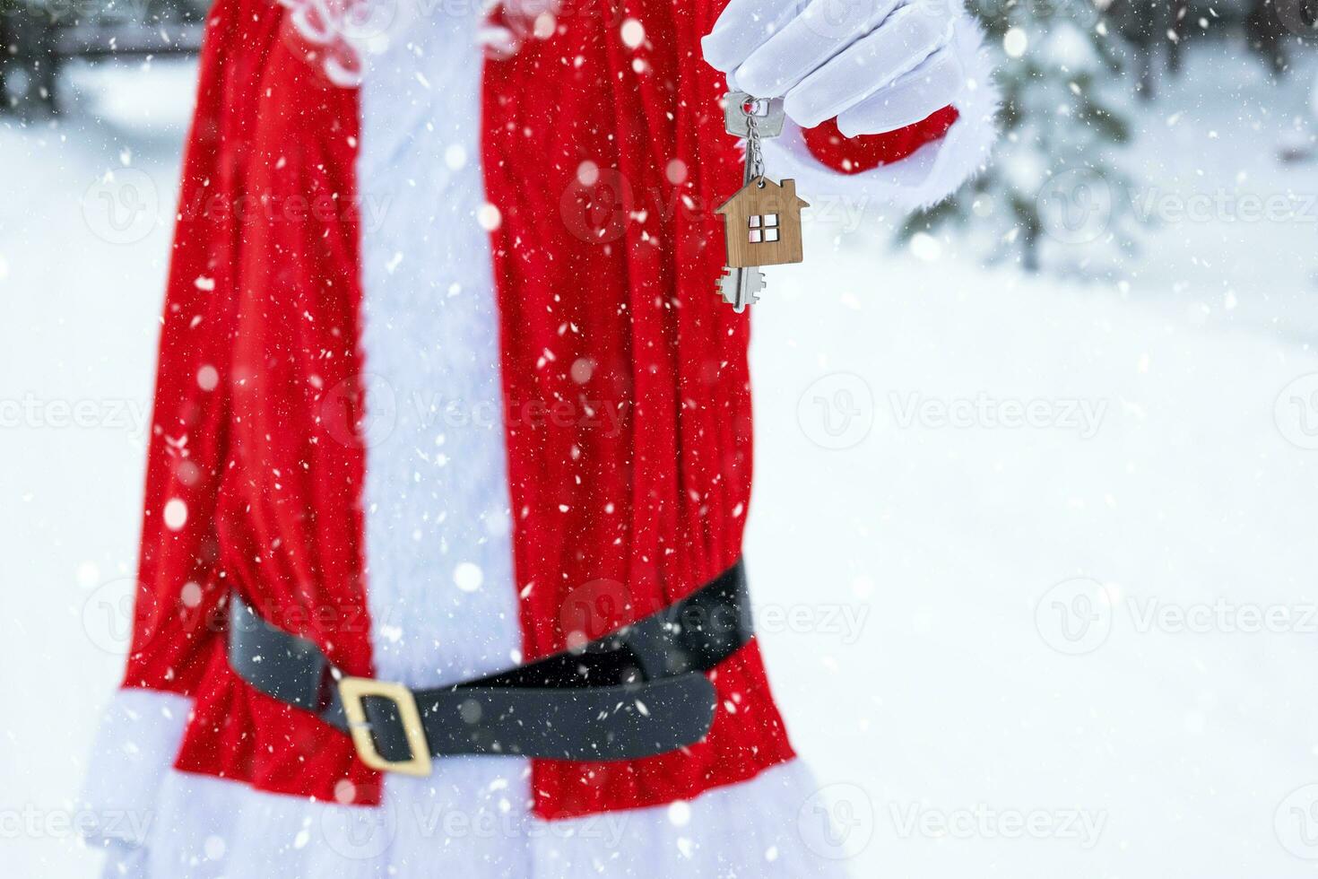 House key with keychain cottage in hands of Santa Claus outdoor in snow. Deal for real estate, purchase, construction, relocation, mortgage. Cozy home. Merry Christmas, new year booking event and hall photo