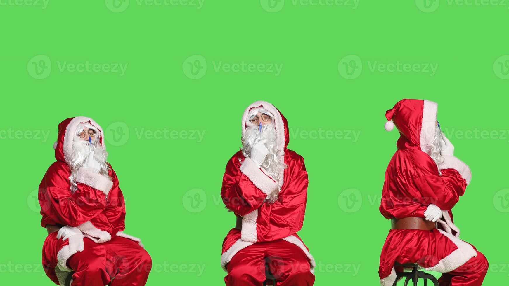 Santa on chair brainstorm gift ideas sitting over greenscreen backdrop, thinking about presents before christmas eve holiday celebration. Young man dressed as saint nick in studio. photo