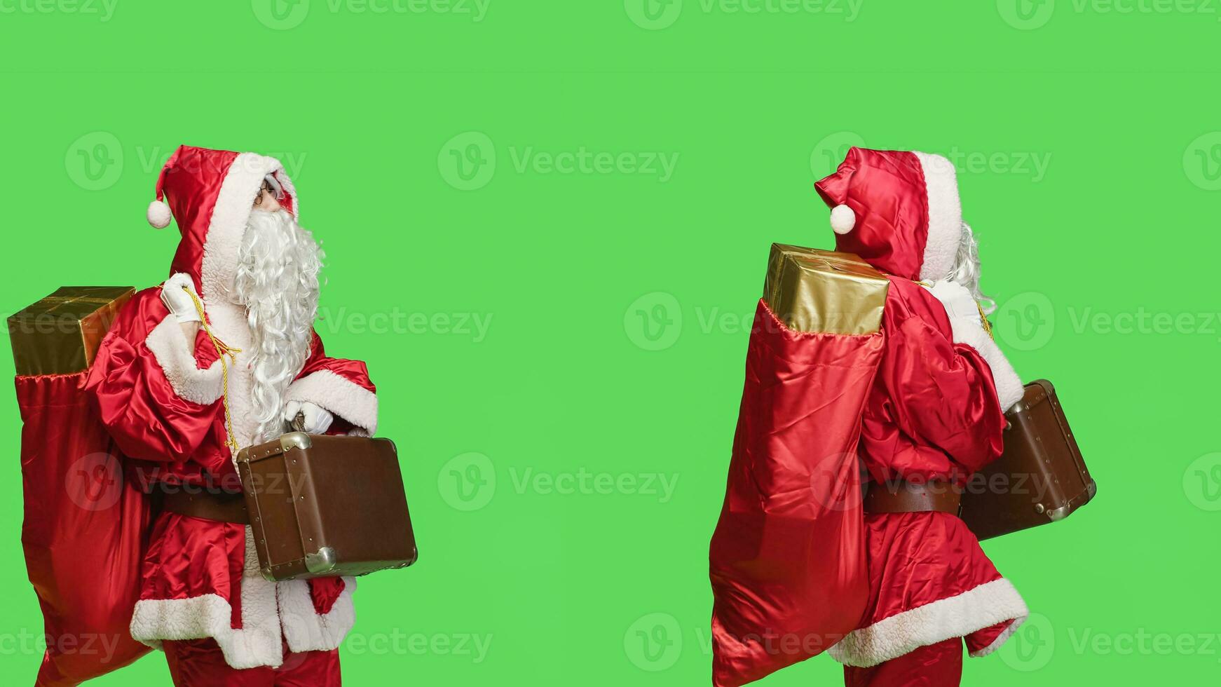 Joyful adult disguised in santa suit holding suitcase and waiting for something in studio with greenscreen backdrop. Positive person carrying briefcase during holiday season celebration. photo