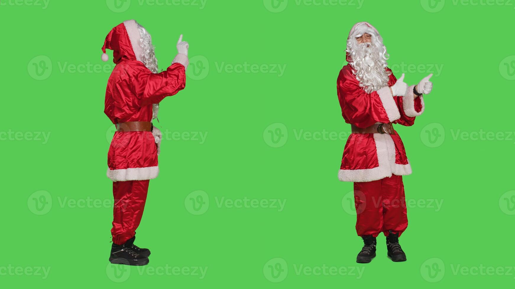 Santa does no sign and gives thumbs up on both sides on the full body greenscreen studio, wearing festive red suit and hat. Father christmas expressing frustration, doing like agreement symbol. photo