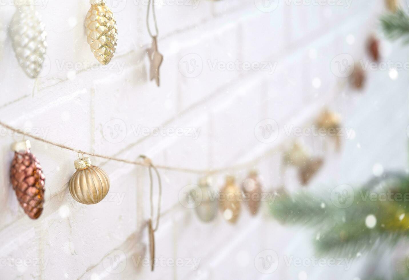 Glass Christmas toys on a jute rope hang on a white brick wall - a festive loft-style decor, a New Year mood. copy space photo