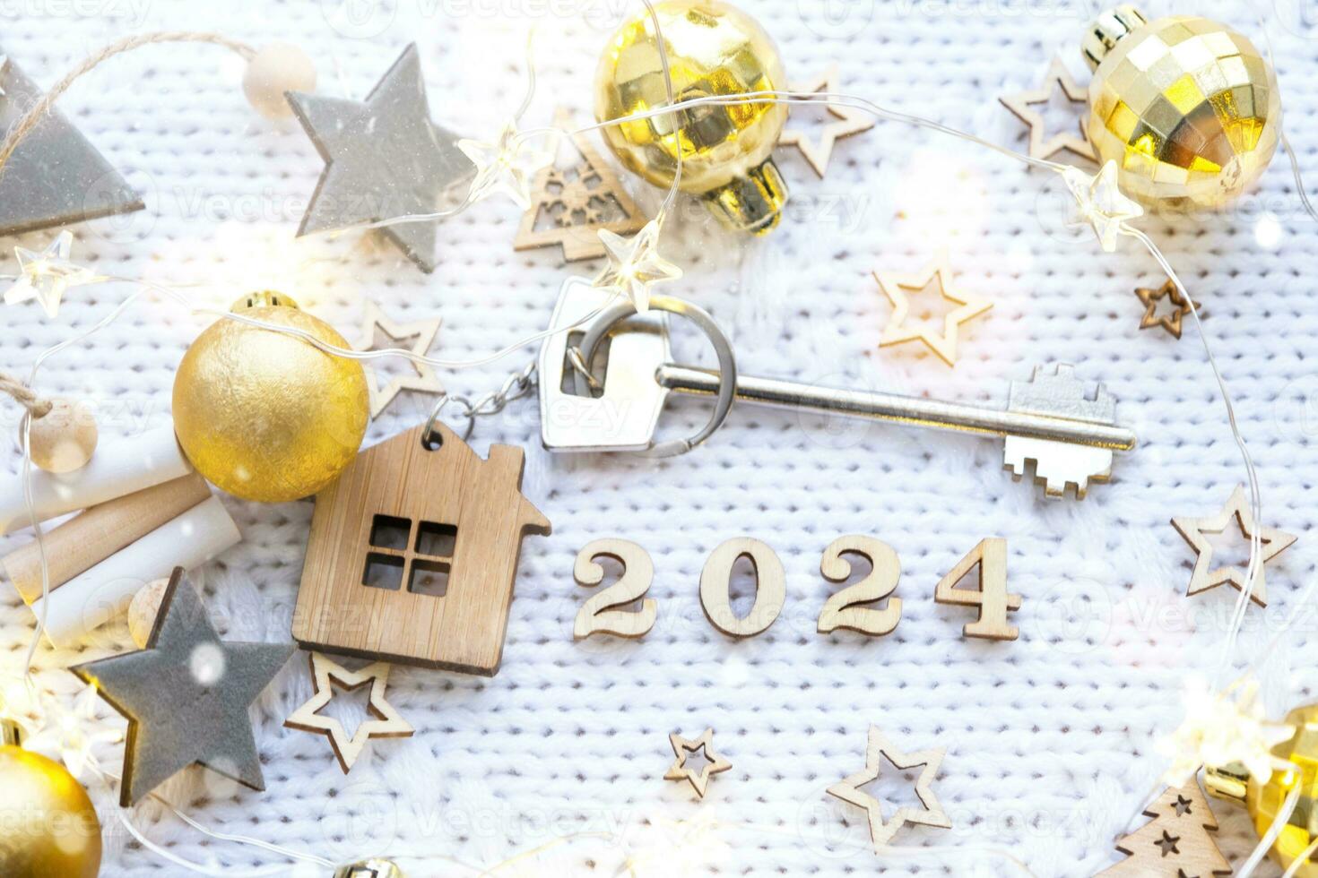 House key with keychain cottage on festive background with stars, lights of garlands. New Year 2024 wooden letters, greeting card. Purchase, construction, relocation, mortgage, insurance photo