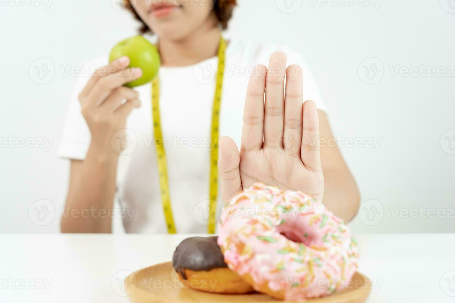 Diet and dieting. Beauty slim female body confuse donut. Woman in exercise clothes achieves weight loss goal for healthy life, crazy about thinness, thin waist, nutritionist. photo