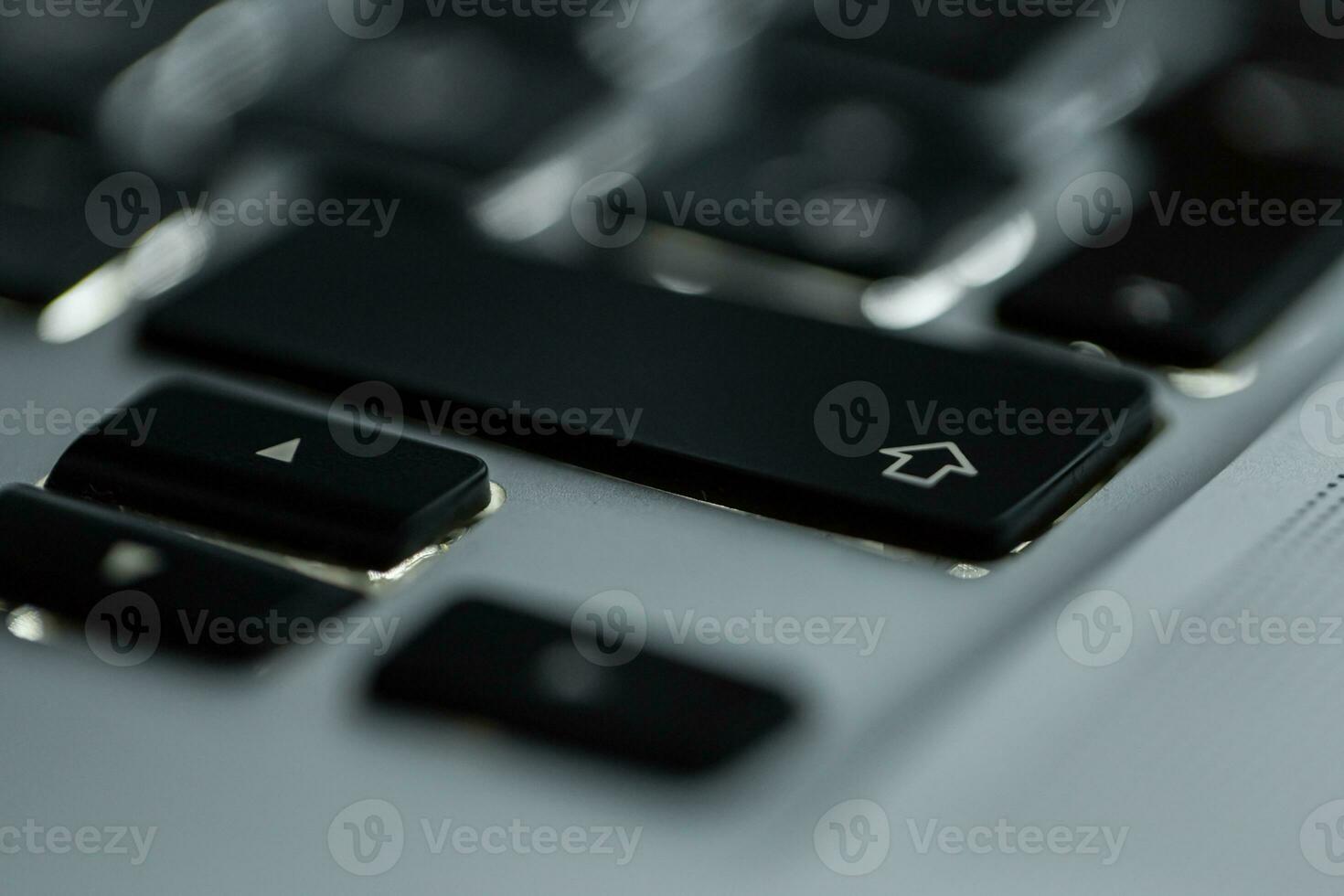 Backlit computer keyboard with focus on shift button, close-up photo