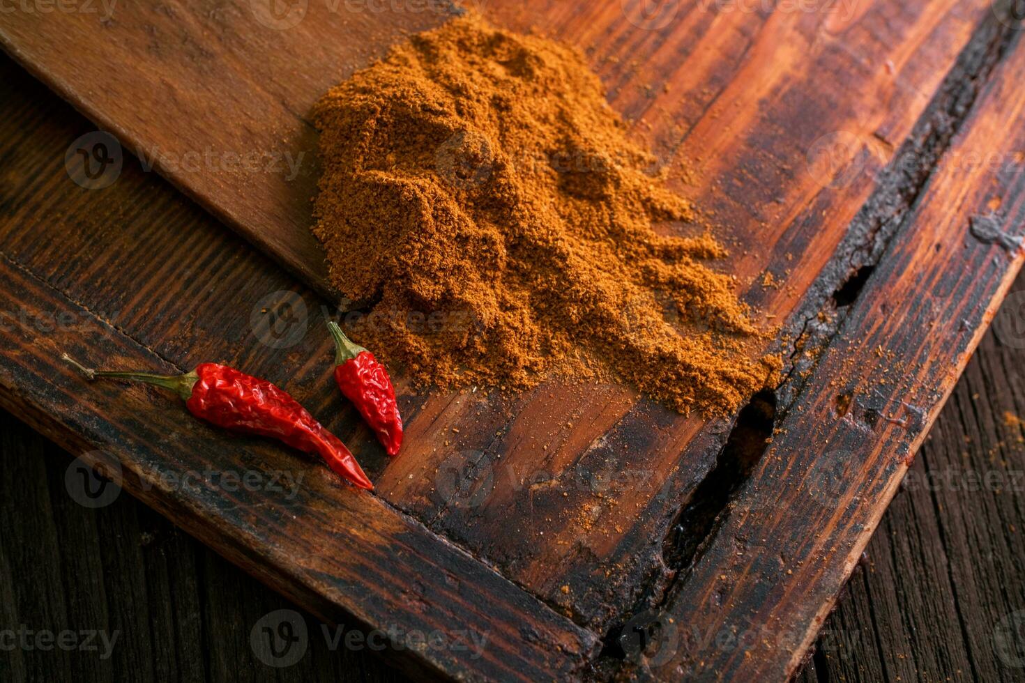 Delicious spicy ground seasoning with red dried peppers on a wooden brown table photo