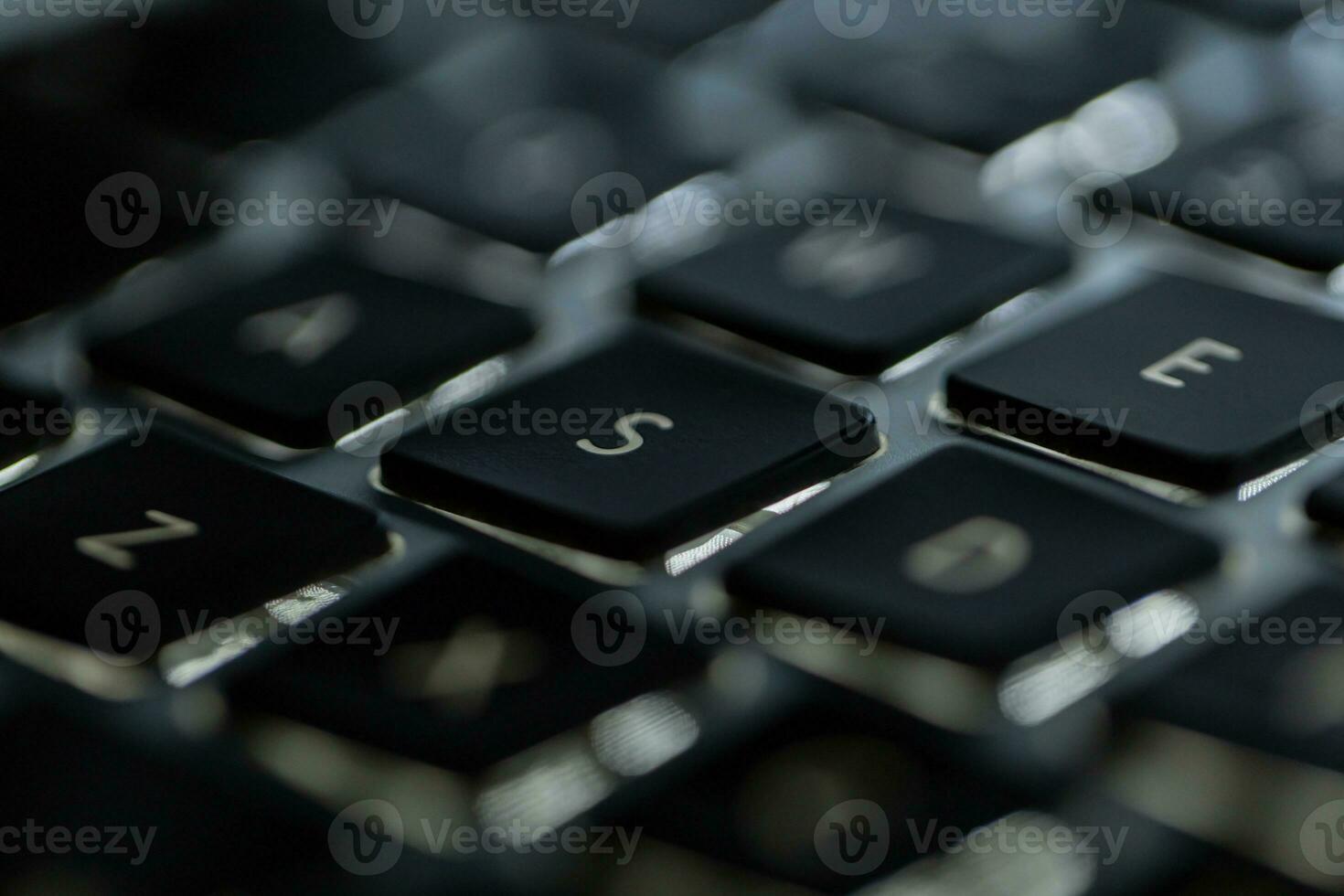 Modern laptop keyboard with backlit, focus on the letter A photo