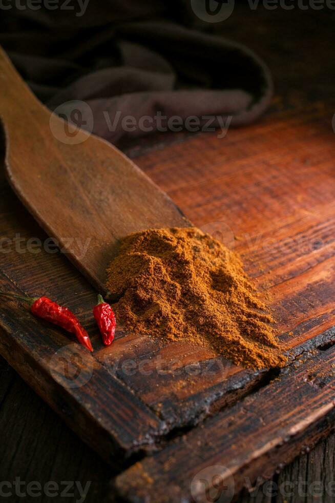 Delicious spicy pepper seasoning with dried red chili peppers on a vintage brown wooden board photo