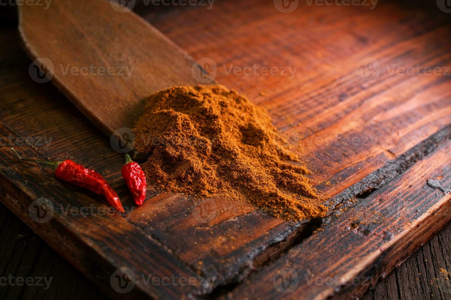 Ground seasoning and spices with spicy dried red chili peppers on a wooden board in a dark background photo