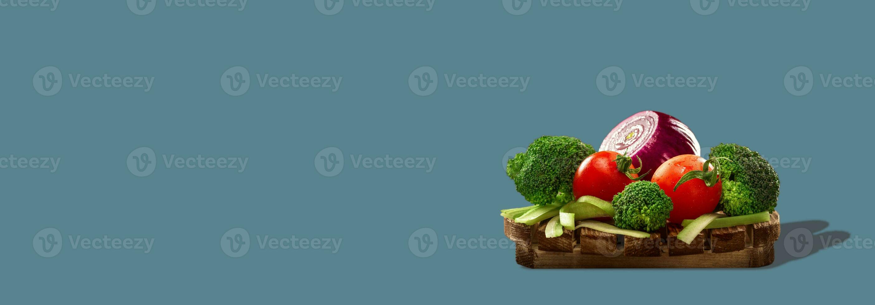 Healthy vegetables on round wooden board isolated on gray background. Photo with copy space.