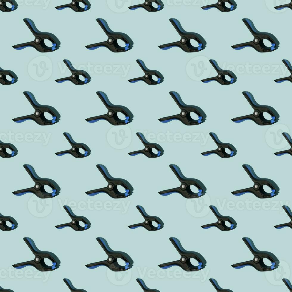 Seamless pattern of black multipurpose clamps with blue grips. Blue background. photo