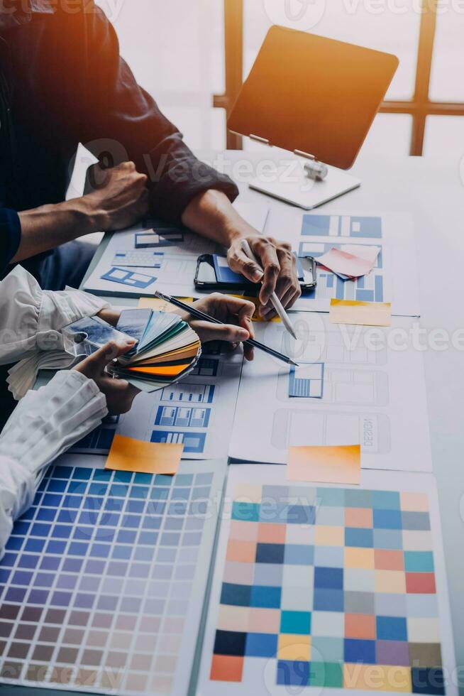 Close up ux developer and ui designer brainstorming about mobile app interface wireframe design on table with customer breif and color code at modern office.Creative digital development agency photo