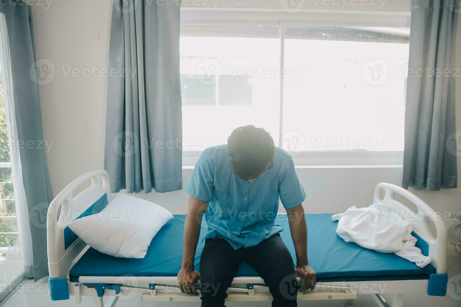 Depressed senior man sitting on the hospital bed alone at night, he feels lonely and abandoned photo