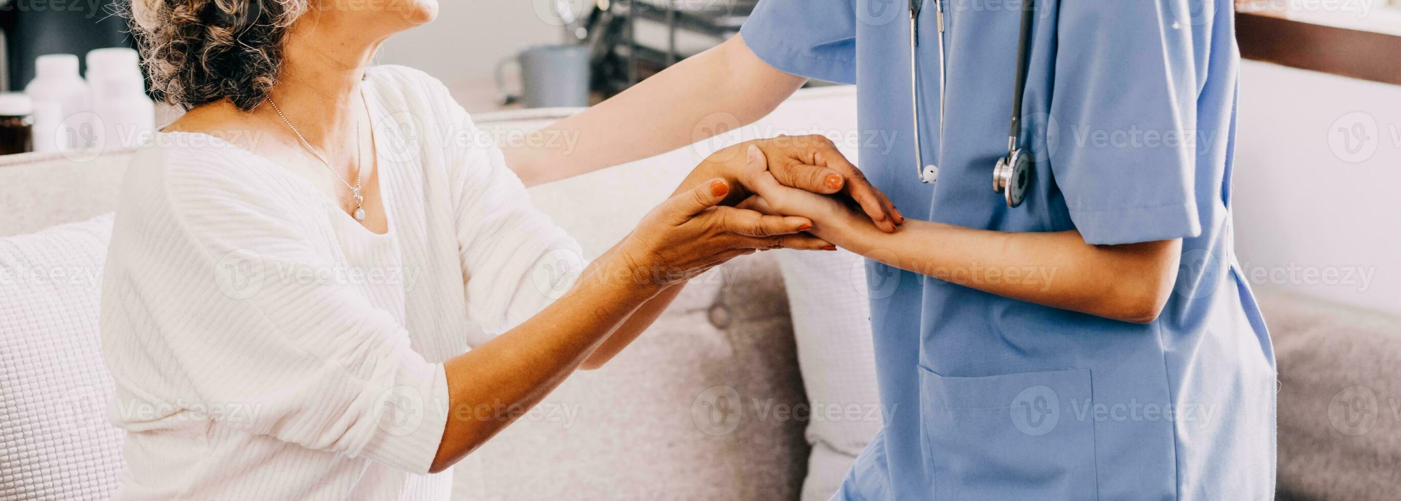 Happy young female nurse provide care medical service help support smiling old grandma at homecare medical visit, lady carer doctor give empathy encourage retired patient sit on sofa at home hospital photo